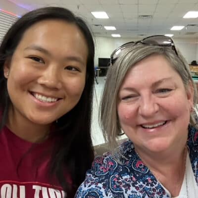 Two women smiling for a selfie indoors.
