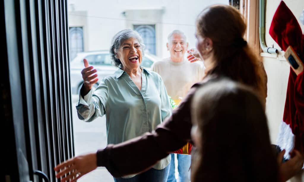 Older couple joyfully greeting family at the door.