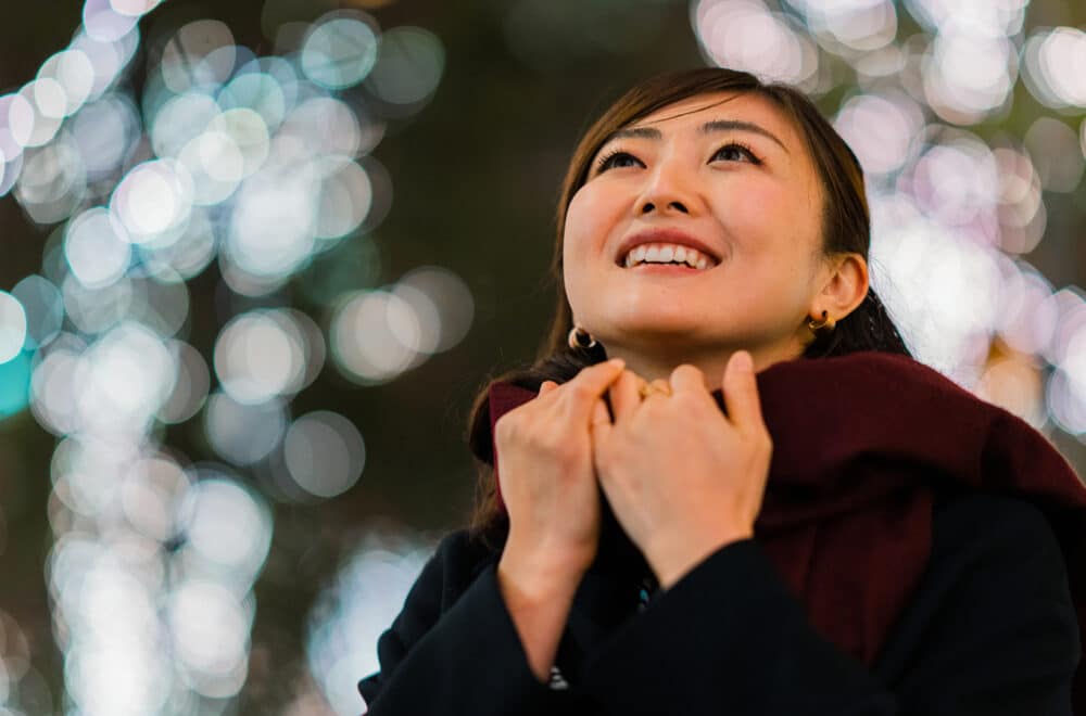A portrait of a woman in an illuminated street at night.