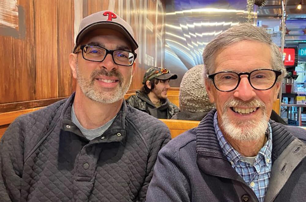 Two men smiling while sitting in a restaurant booth.
