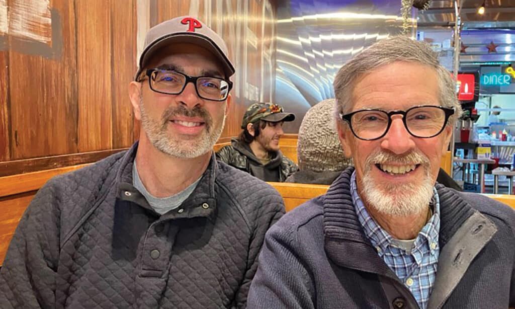 Two men smiling while sitting in a restaurant booth.