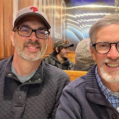 Two men smiling while sitting in a restaurant booth.
