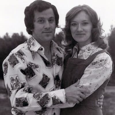 A man and woman stand, embracing each other in a black-and-white image.