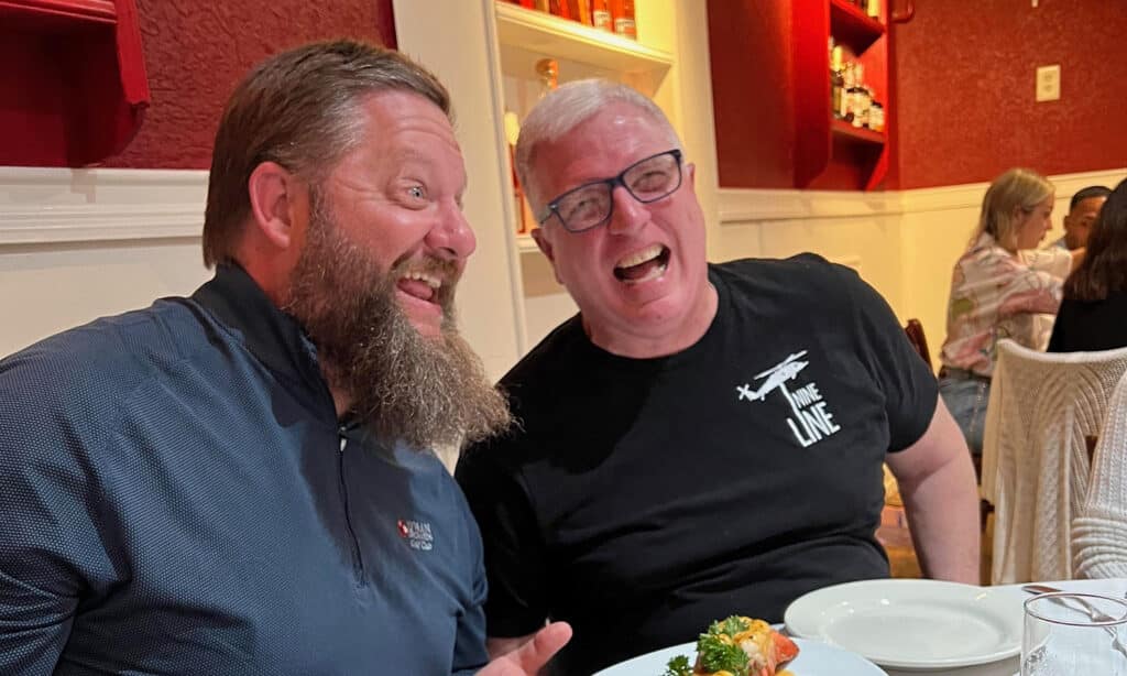 Two men sitting in a restaurant laughing.